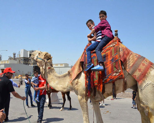 Two children riding a camel celebrate International Family Day in Jordan Bromine Company